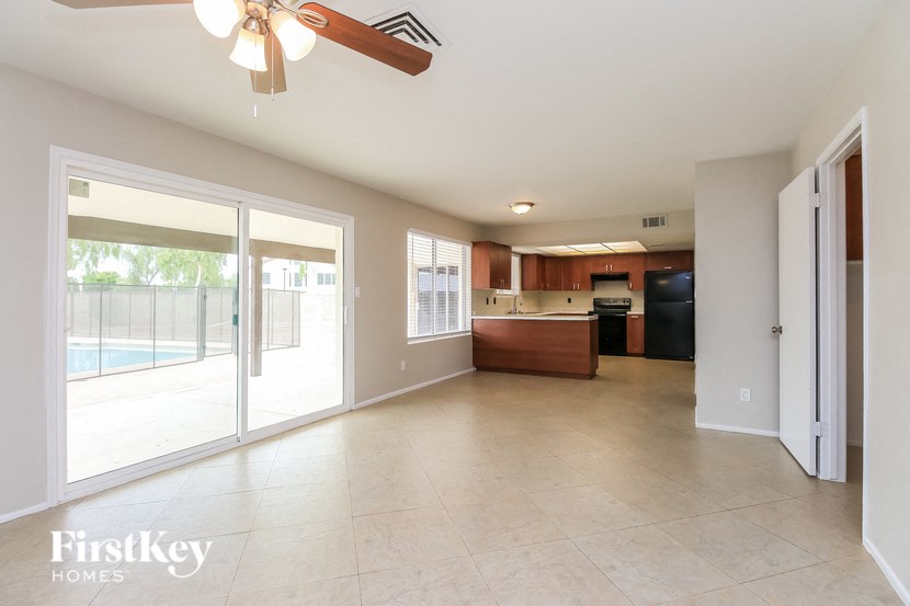 an empty living room and kitchen with a ceiling fan