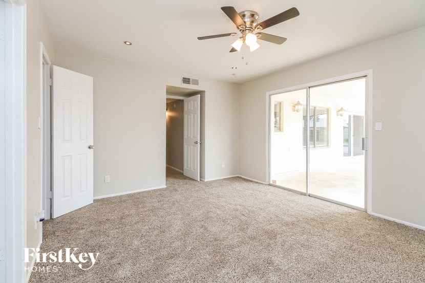 an empty living room with a ceiling fan and glass doors