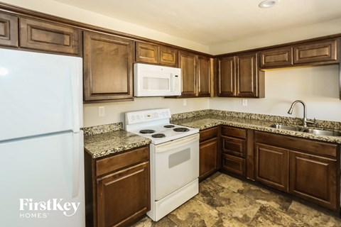 A kitchen with brown cabinets and a white fridge.