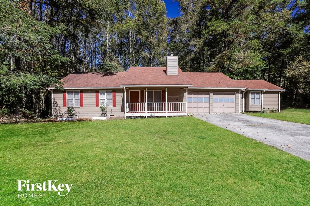 A house with a red roof and a chimney is surrounded by trees.