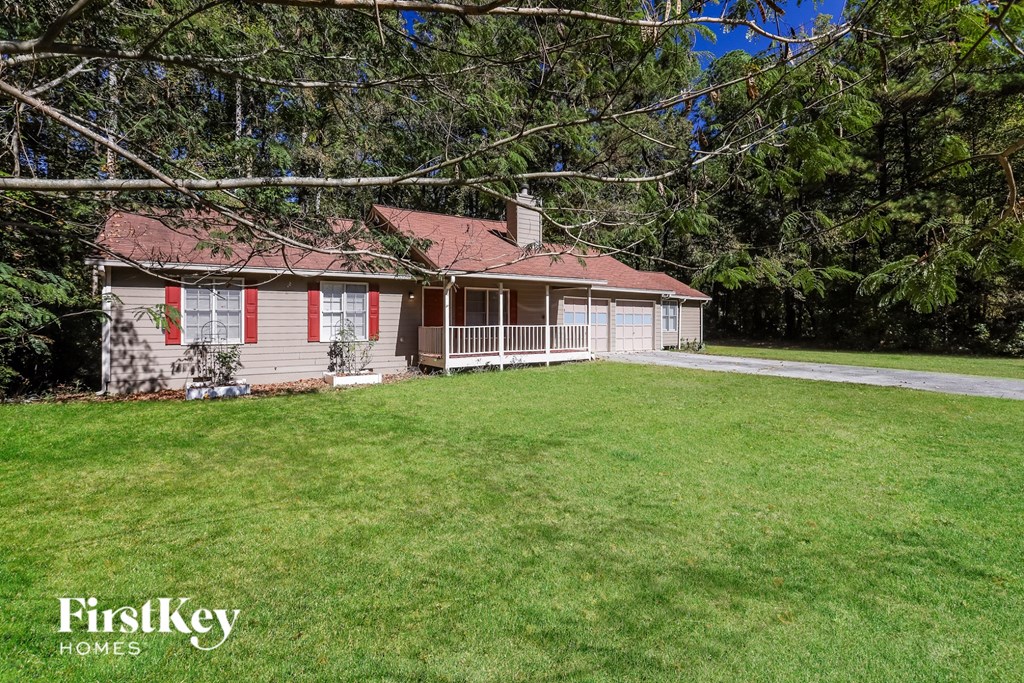 A house with a red roof and a porch is surrounded by trees.