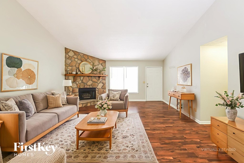 A living room with a stone fireplace and a wooden coffee table.