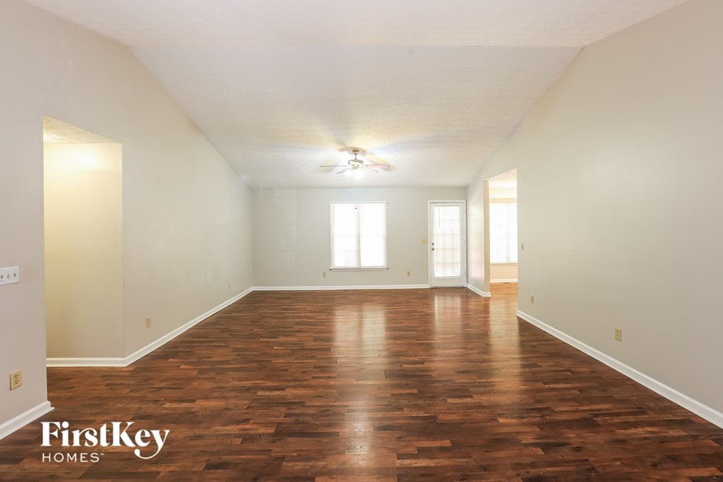 A spacious room with wooden floors and a ceiling fan.
