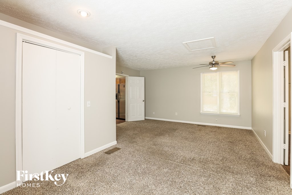 A spacious room with a carpeted floor and a ceiling fan.