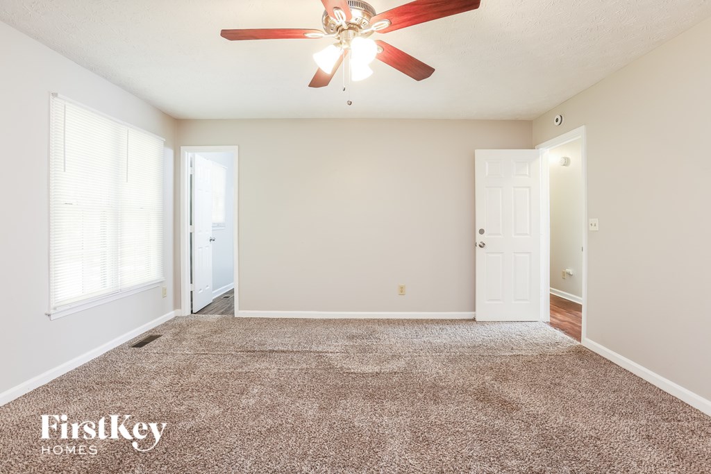 A spacious room with a fan and carpeted floor.