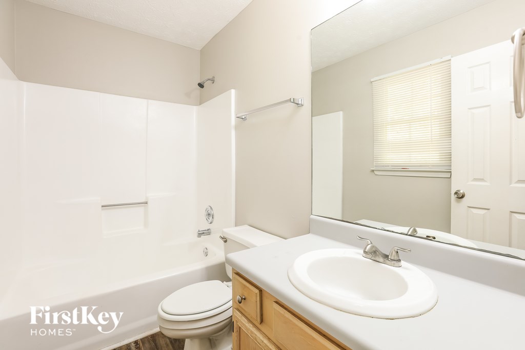 A white bathroom with a toilet, sink, and mirror.