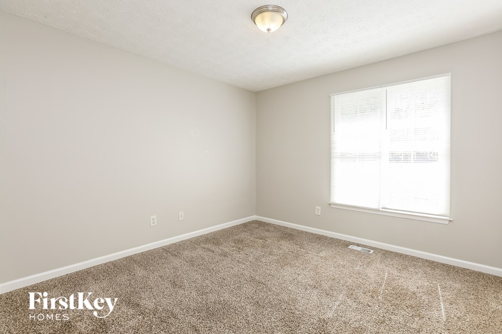A room with a carpeted floor and a window with blinds.