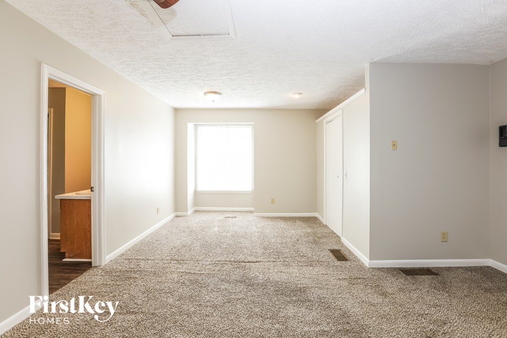 A spacious room with a carpeted floor and a door on the left.