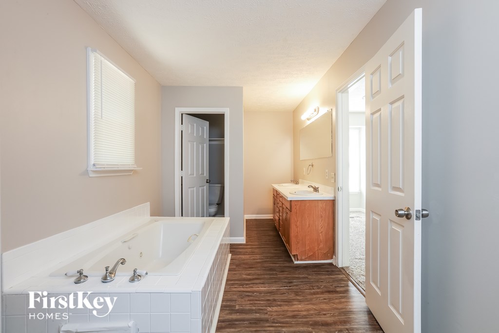 A white bathroom with a large sink and a wooden cabinet.