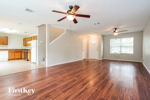 A spacious room with wooden floors and a ceiling fan.