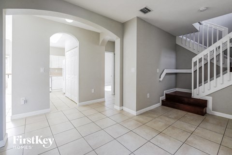 a large entryway with a staircase and tiled flooring