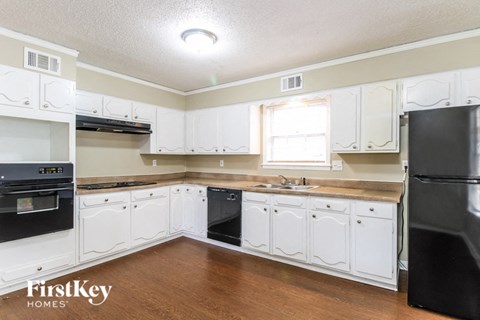 a kitchen with white cabinets and black appliances