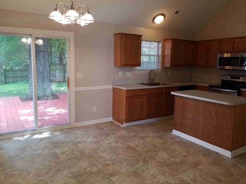 A kitchen with wooden cabinets and a tiled floor.