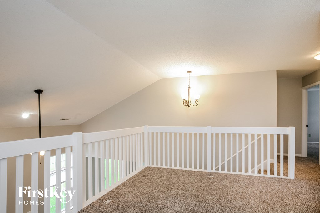 the loft has a landing with a white railing and a chandelier