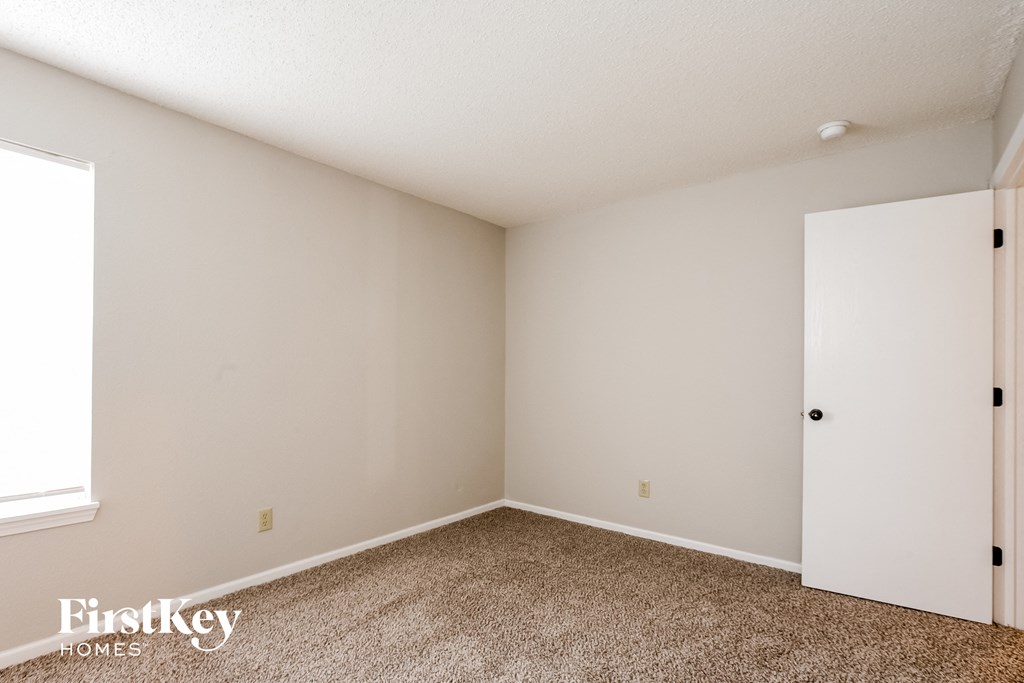 a bedroom with white walls and carpet and a white door