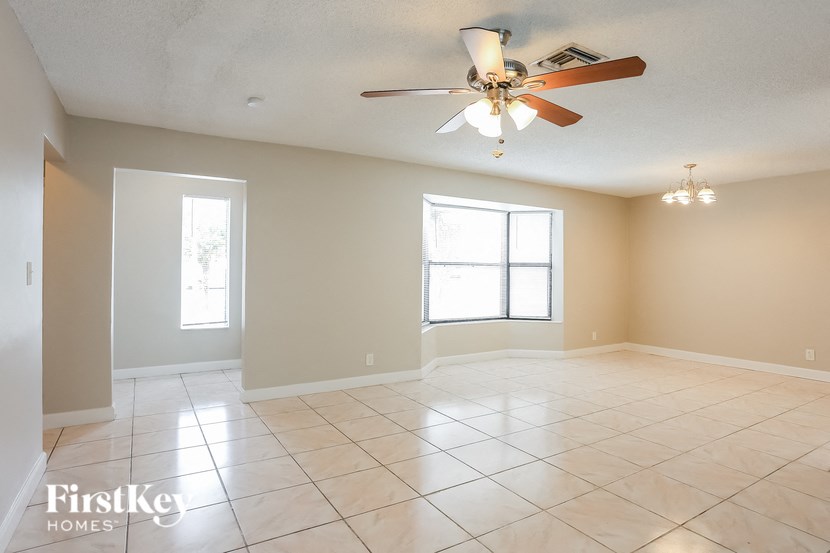 A spacious room with a ceiling fan and large windows.