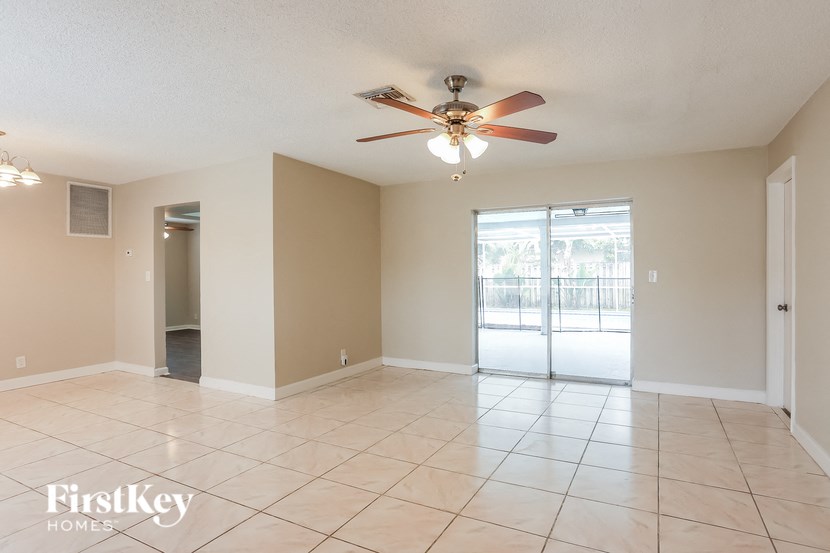 A spacious room with a ceiling fan and sliding glass doors leading to a balcony.