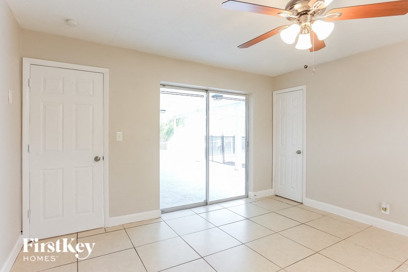 A room with a ceiling fan and sliding glass doors.