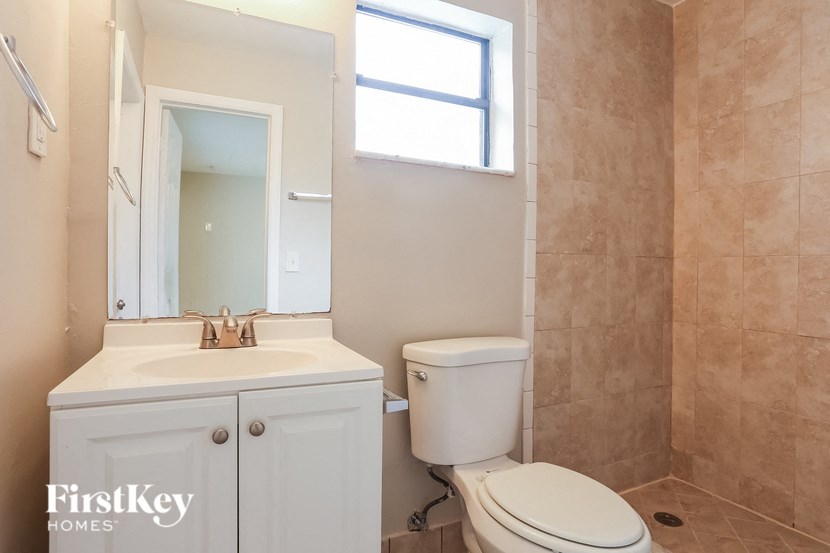 A bathroom with a toilet, sink, and mirror.