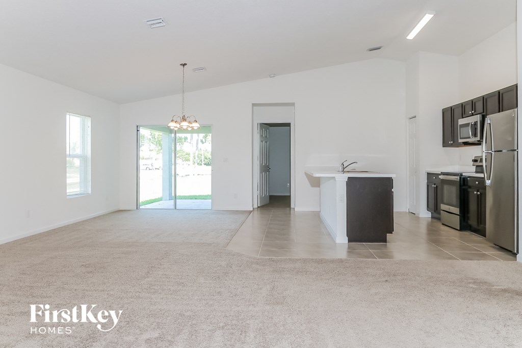 an empty kitchen and living room with stainless steel appliances and tile flooring