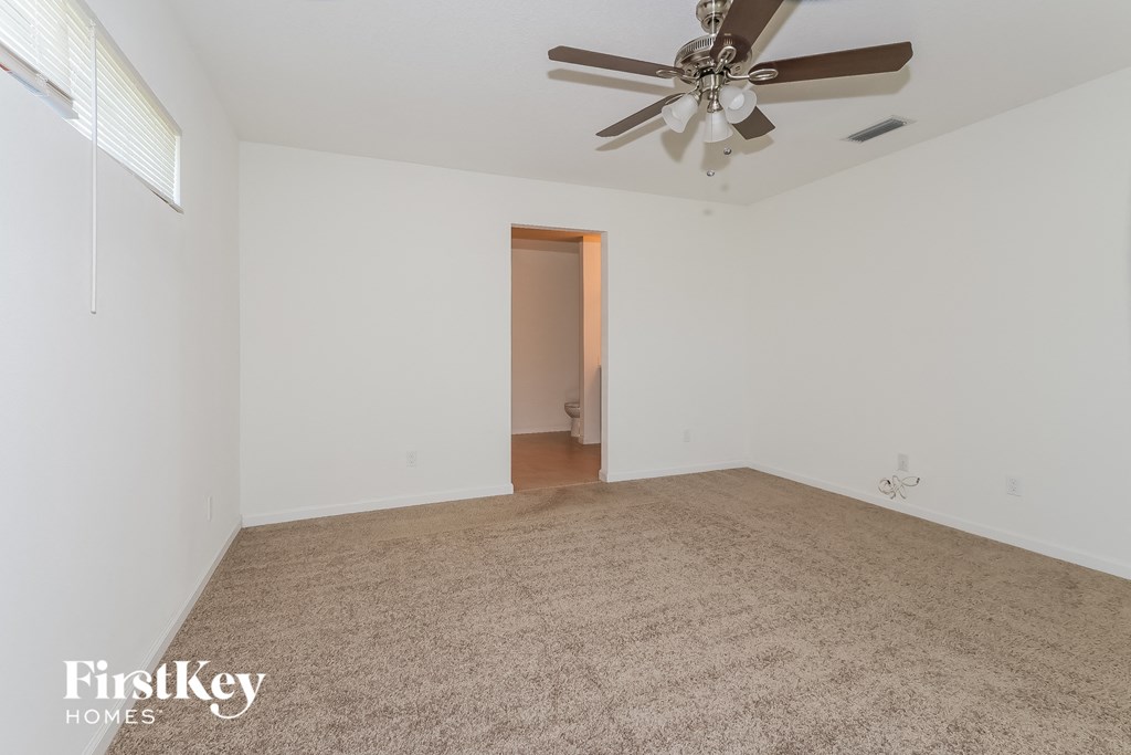 an empty living room with a ceiling fan and carpet