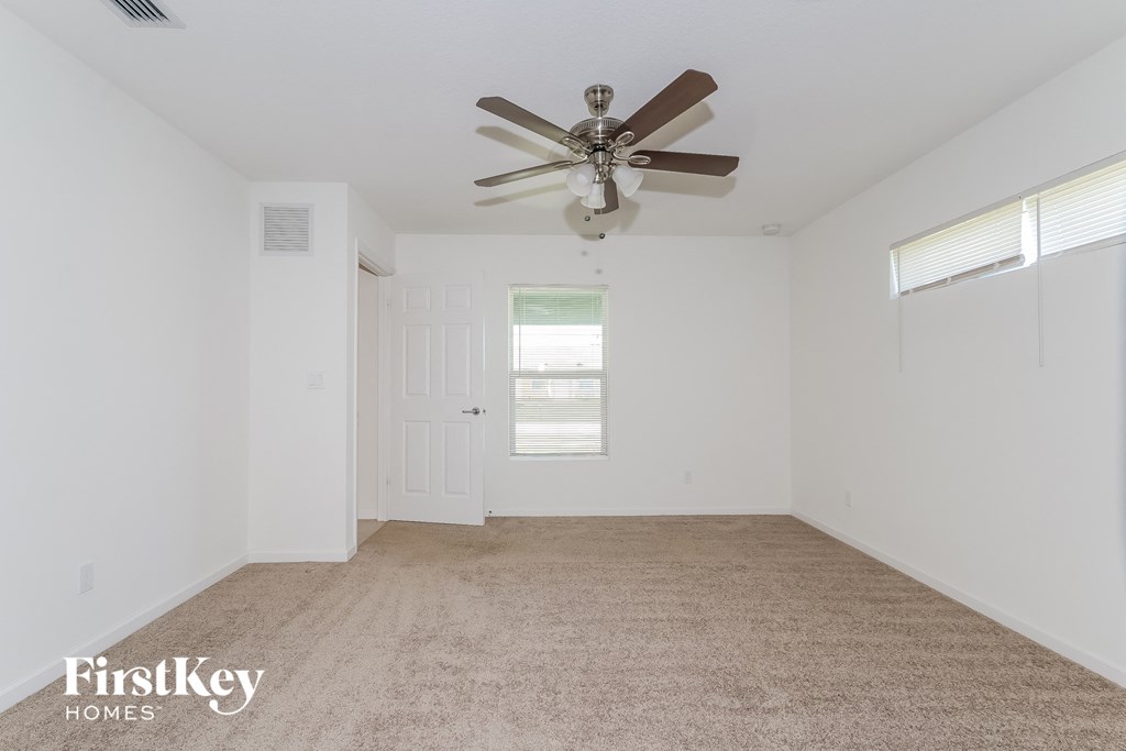 a white room with a ceiling fan and a carpet