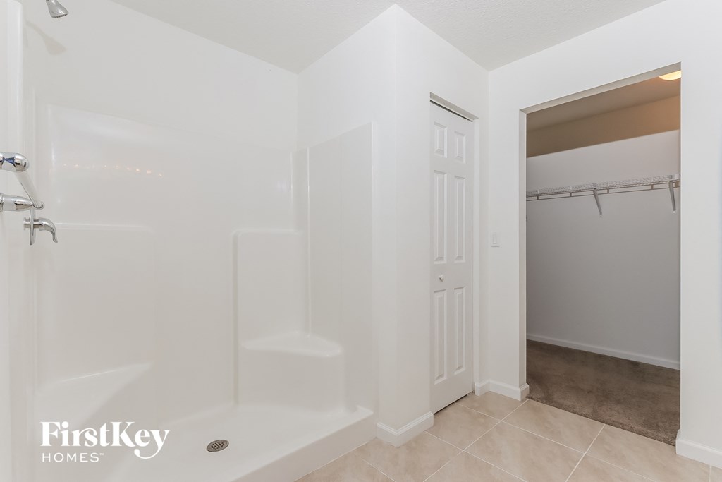 a white bathroom with a shower and a door to a closet