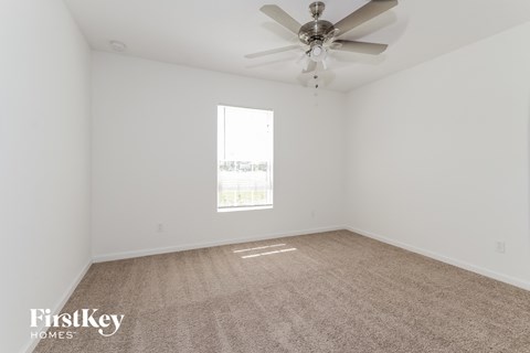 a spacious living room with white walls and a ceiling fan
