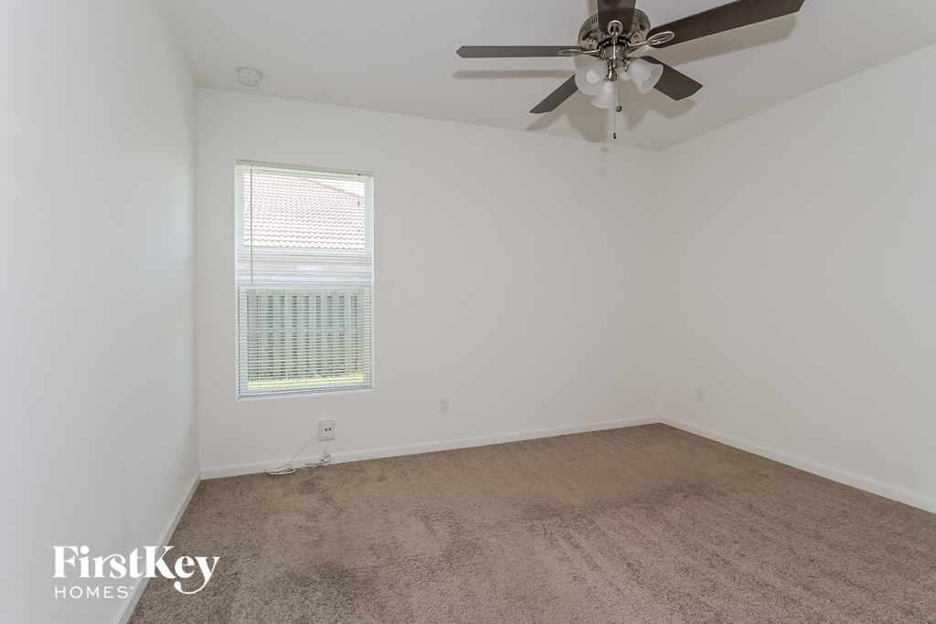 a bedroom with white walls and a ceiling fan