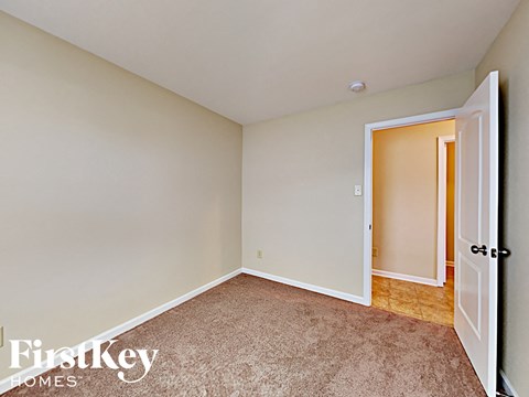 A room with a carpeted floor and a door on the right.