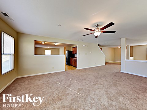 A spacious room with a ceiling fan and a carpeted floor.