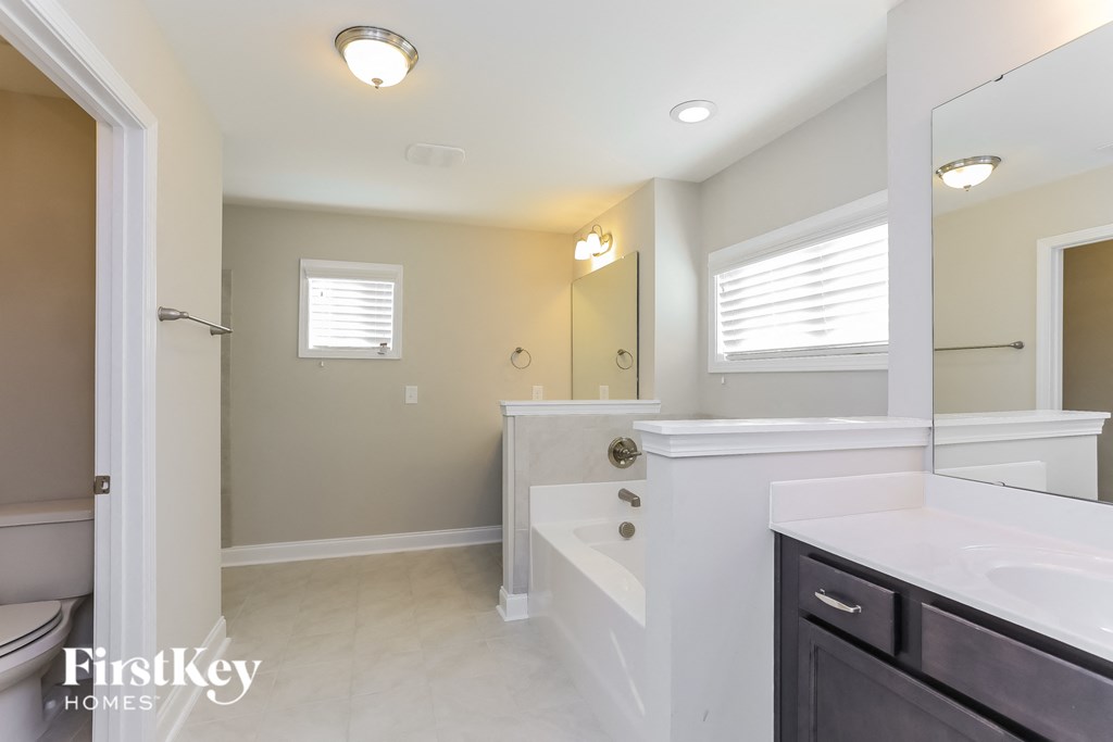 a white bathroom with a tub and a sink and a mirror