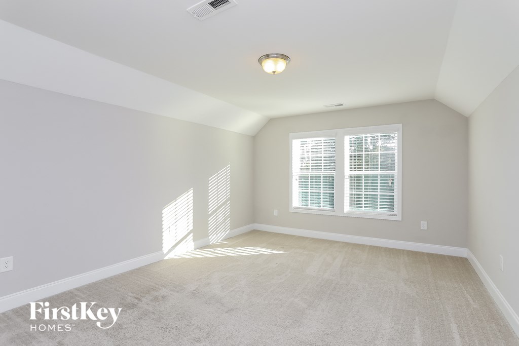 a spacious living room with a large window and a carpeted floor