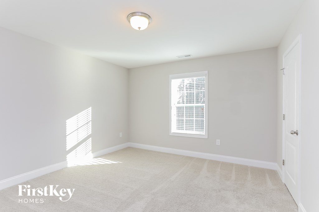 a spacious living room with white carpet and a window