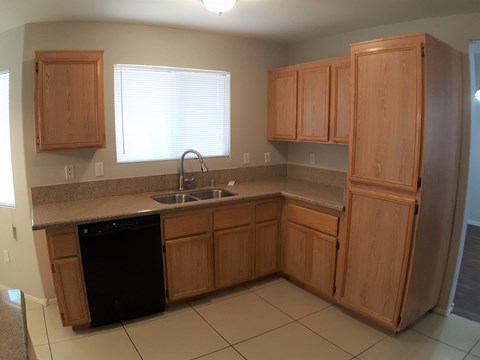 A kitchen with wooden cabinets and a black dishwasher.