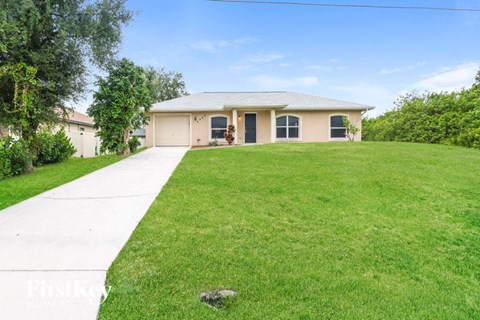 a beige house with a lawn and a sidewalk