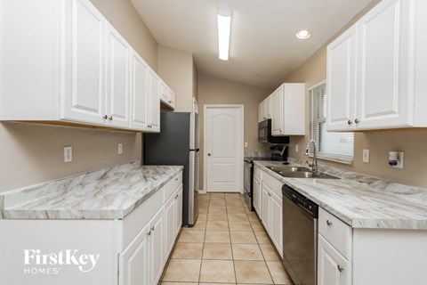 a kitchen with white cabinets and marble counter tops and a sink