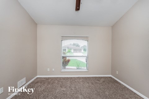 a spacious living room with carpet and a window