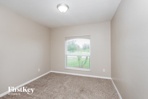 a spacious room with carpet and a window