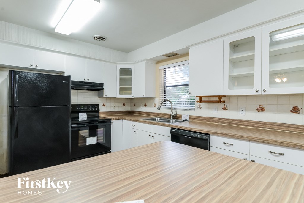 A kitchen with a black fridge and wooden countertops.