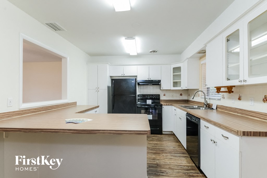 A kitchen with a black fridge and white cabinets.