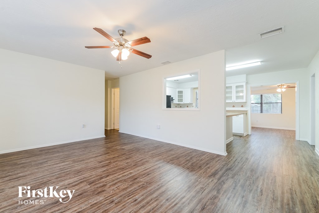 A spacious room with a ceiling fan and wooden flooring.