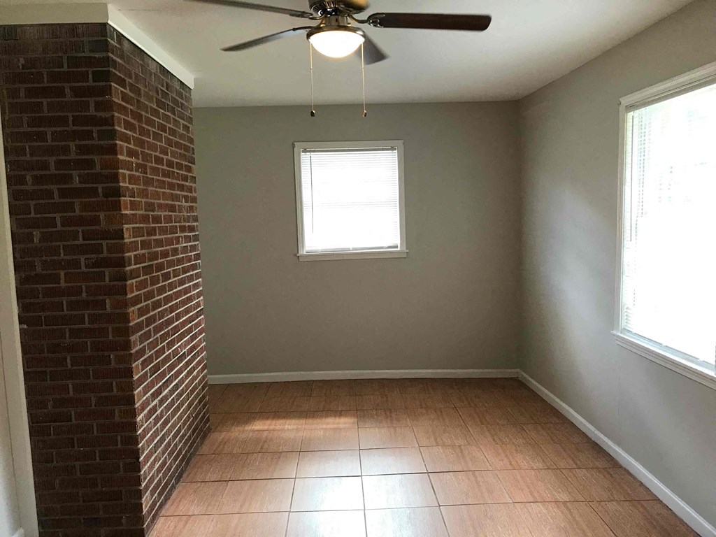an empty room with a ceiling fan and a brick wall