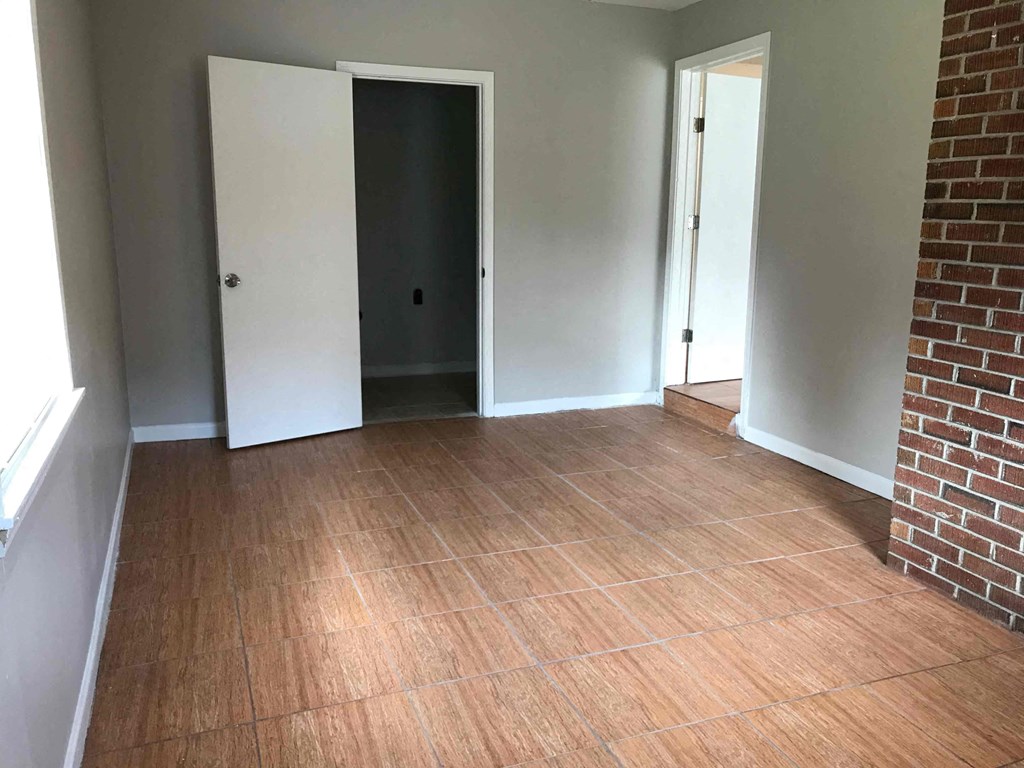 an empty living room with wood floors and a brick wall