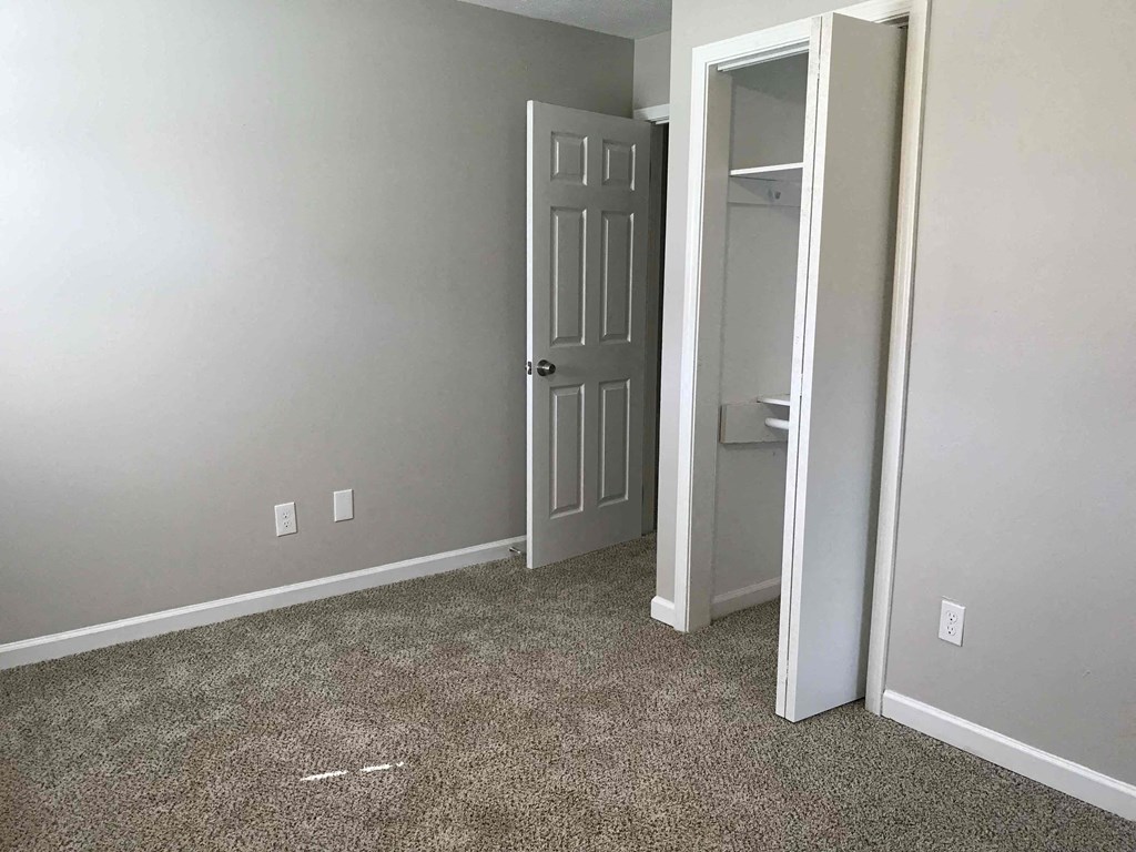 a room with a carpeted floor and a door to a closet