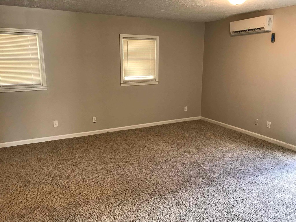a empty room with carpet and two windows