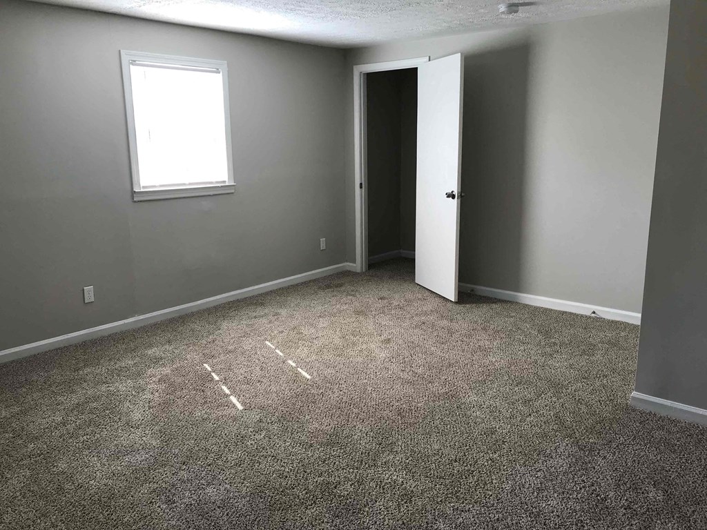 a room with carpet and a door and a window