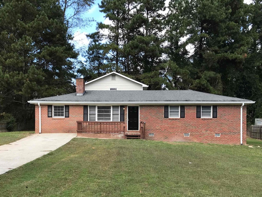 the front of a brick house with a lawn and trees