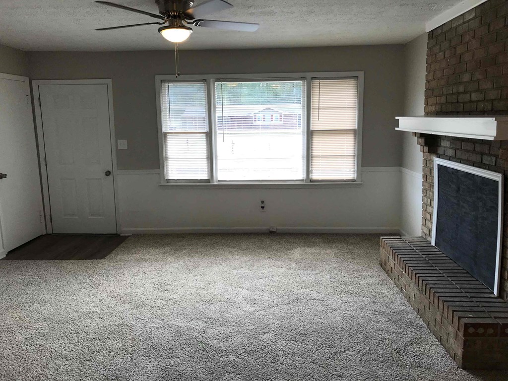 an empty living room with a fireplace and a ceiling fan