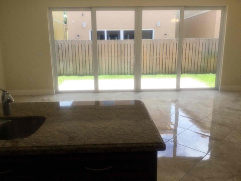 A kitchen with a sink and a window overlooking a wooden fence.